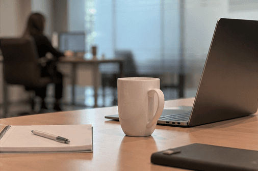 Kaffekopp og notatblokk på kontorpult hos ADMA